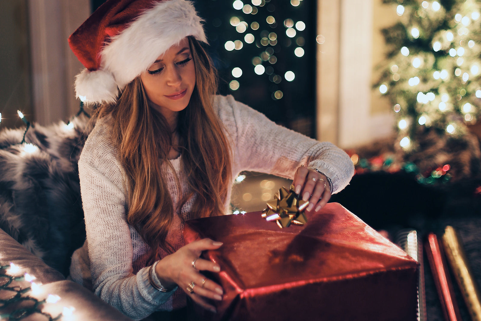 person wearing santa hat and wrapping gift