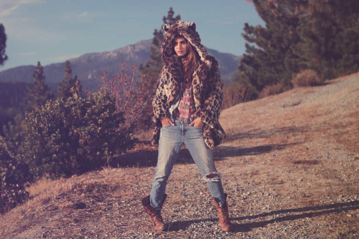 person standing in forest wearing jeans and faux fur coat