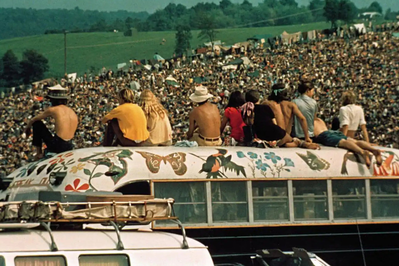 Several men sit on top of a bus in the crowd at Woodstock 1969.