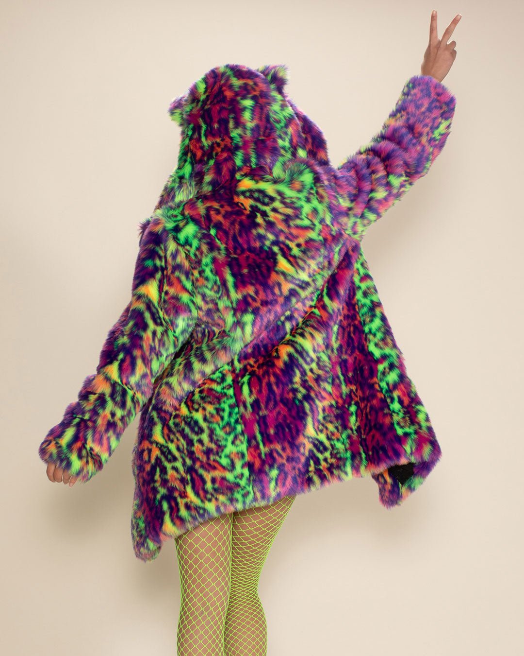 Gal in neon green fishnets throws up a peace sign with her back to the camera, wearing the Neon Disco Leopard Cat Classic faux fur jacket.