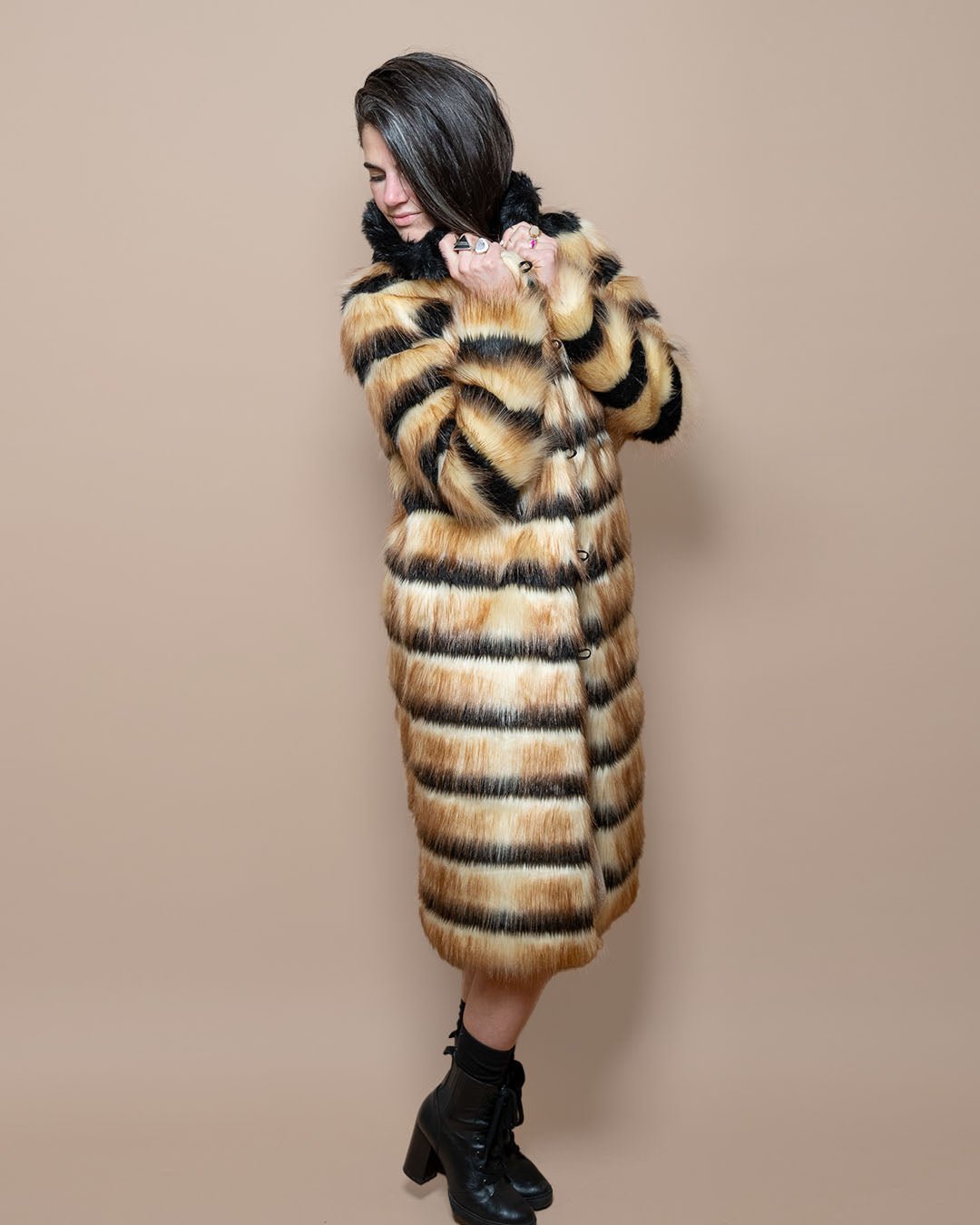 Girl looking demurely to the side in fully closed Gazelle Long Collared Faux Fur Coat, holding the collar with both hands.