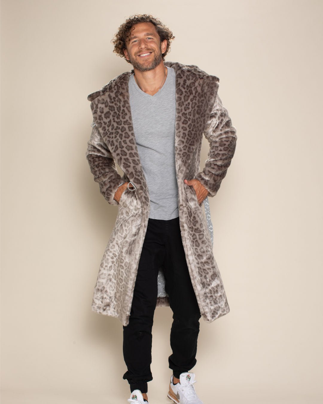 Handsome man smiling with hands in the pockets of the belted Silver Leopard Classic Long Faux Fur Jacket.