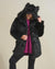 Curvy blonde gal smiling slyly while wearing black wolf hooded faux fur coat with ears.