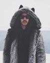 Man with long dark hair wearing sunglasses and a hooded grey faux fur coat.