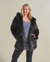 Curvy blonde female model smiling with hands in the pockets of the Panther Black Faux Fur Coat she's wearing. 