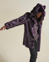 Man model with dreadlocks looking down with one arm extended out and wearing purple midnight wolf fake fur jacket. 