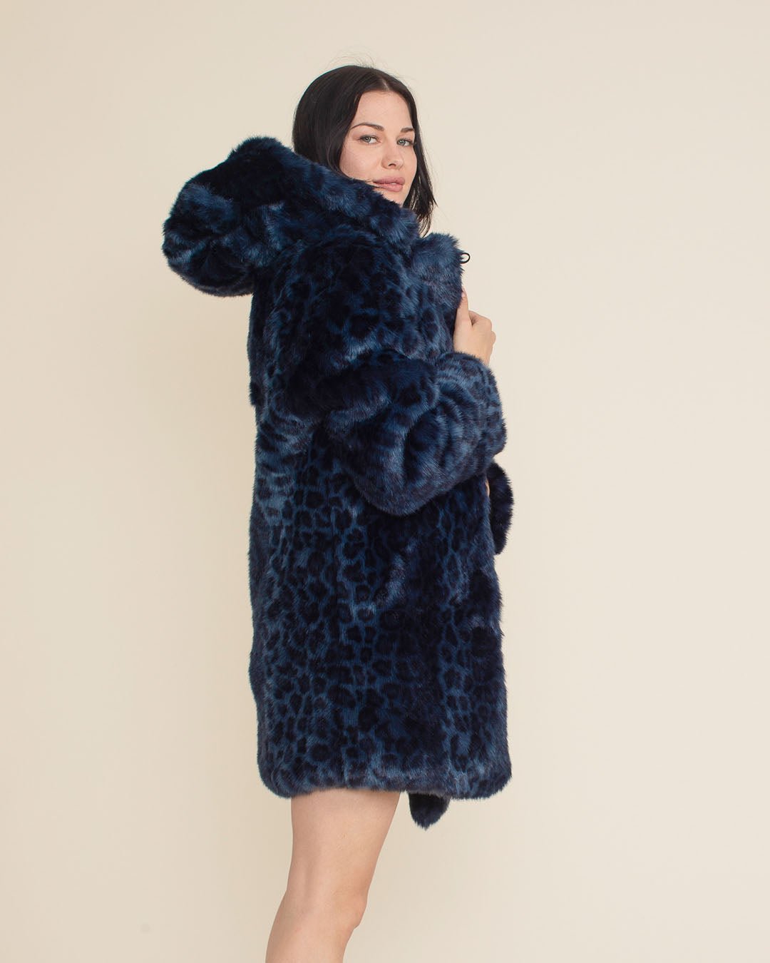 Gal in the Classic Collector Edition Indigo Leopard Faux Fur Coat, looking at the camera while facing to one side, holding the coat closed to showcase the luxe fur.