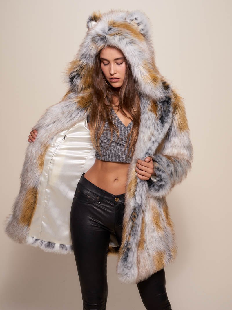 Girl in leather pants wearing a classic Arctic Fox fake fur jacket with the hood and ears open, looking down while holding one side open to showcase the inner liner.