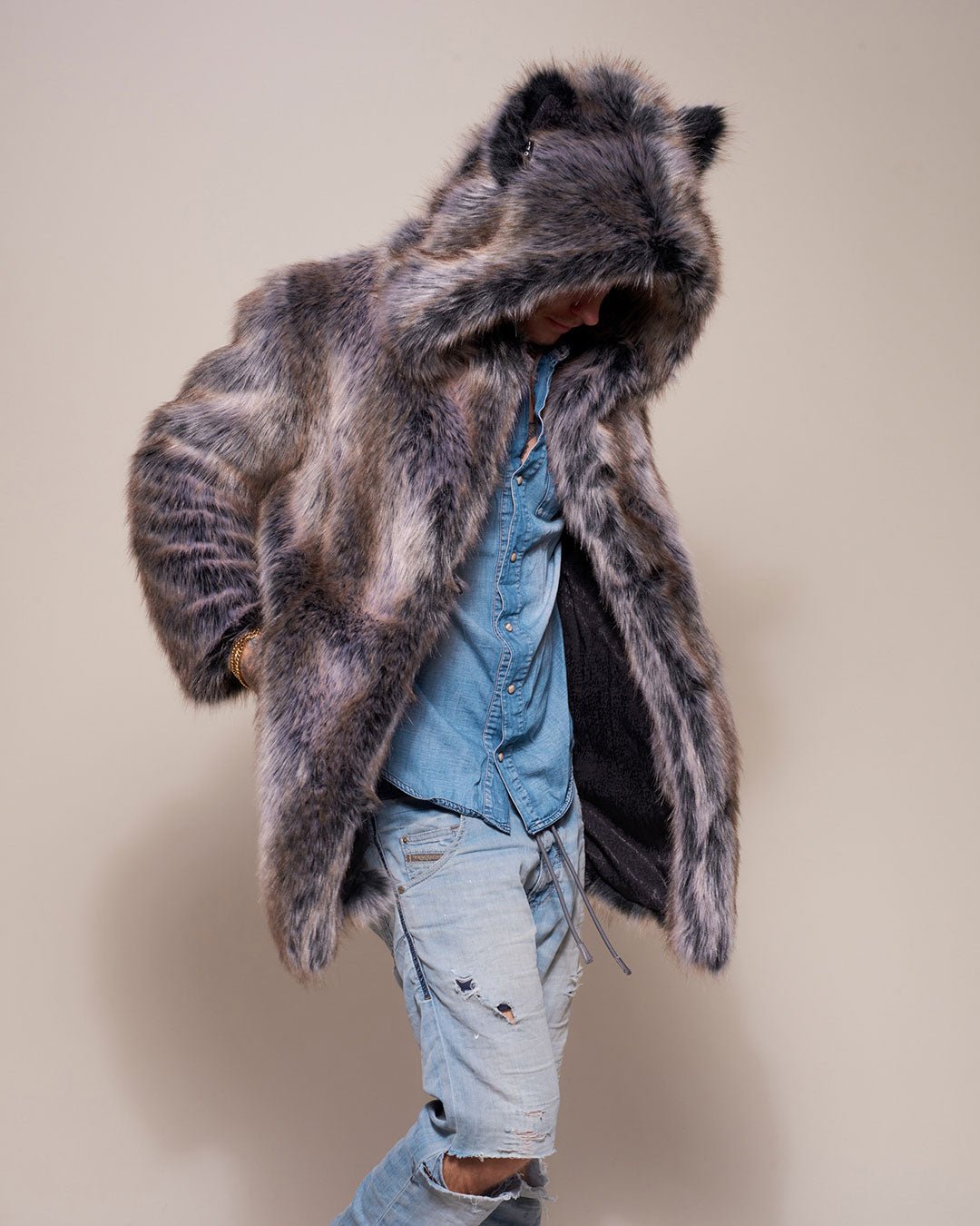 Man Wearing Grey Wolf Classic Faux Fur Coat with hood and ears on side facing looking down with hand in pocket.