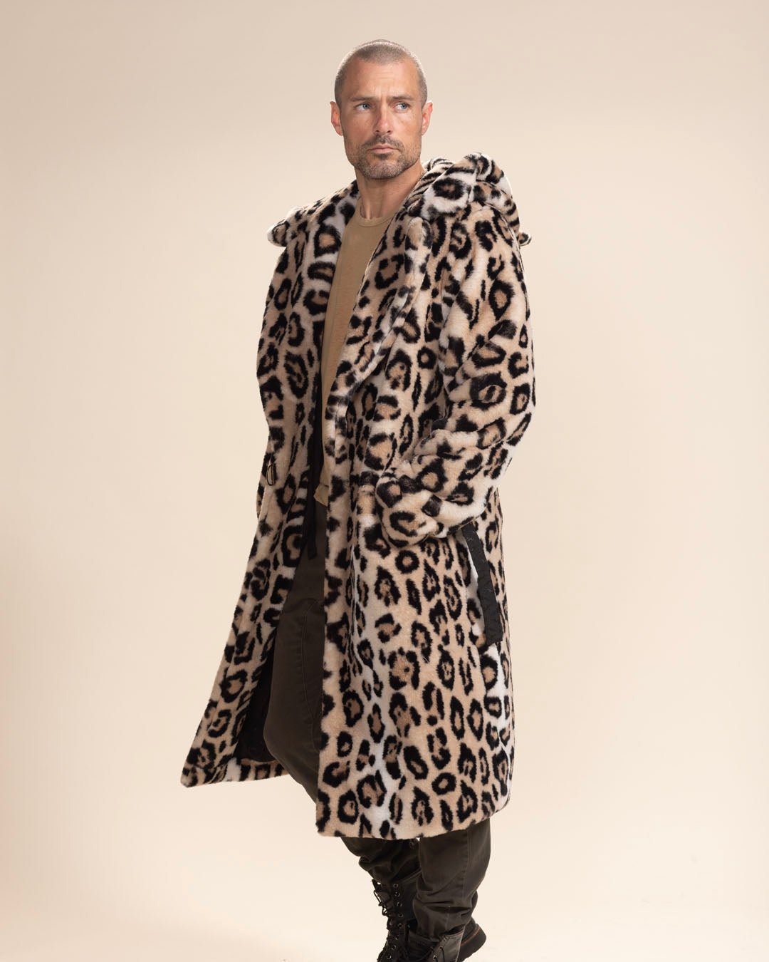 Serious, handsome model gazing into the distance, hands in pockets, wearing Classic Men's Long Faux Fur Coat in Arabian Leopard Print, hood down.