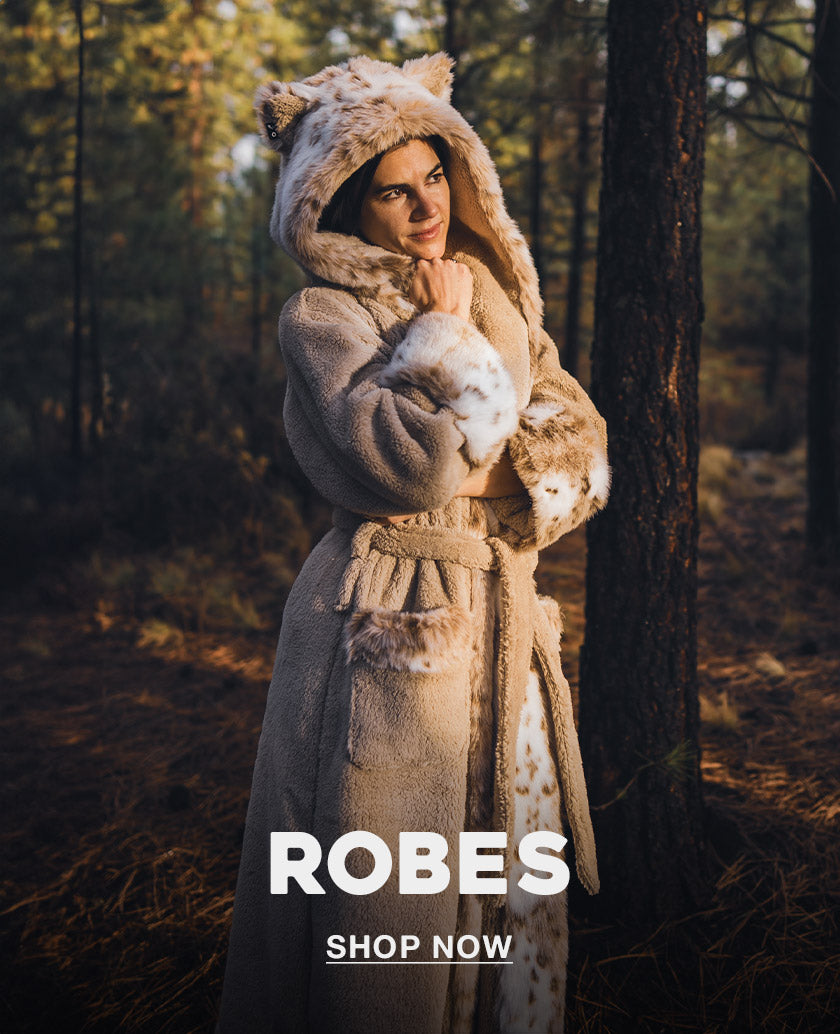 Woman wearing a faux fur bath robe with text at the bottom that says ROBES Shop Now