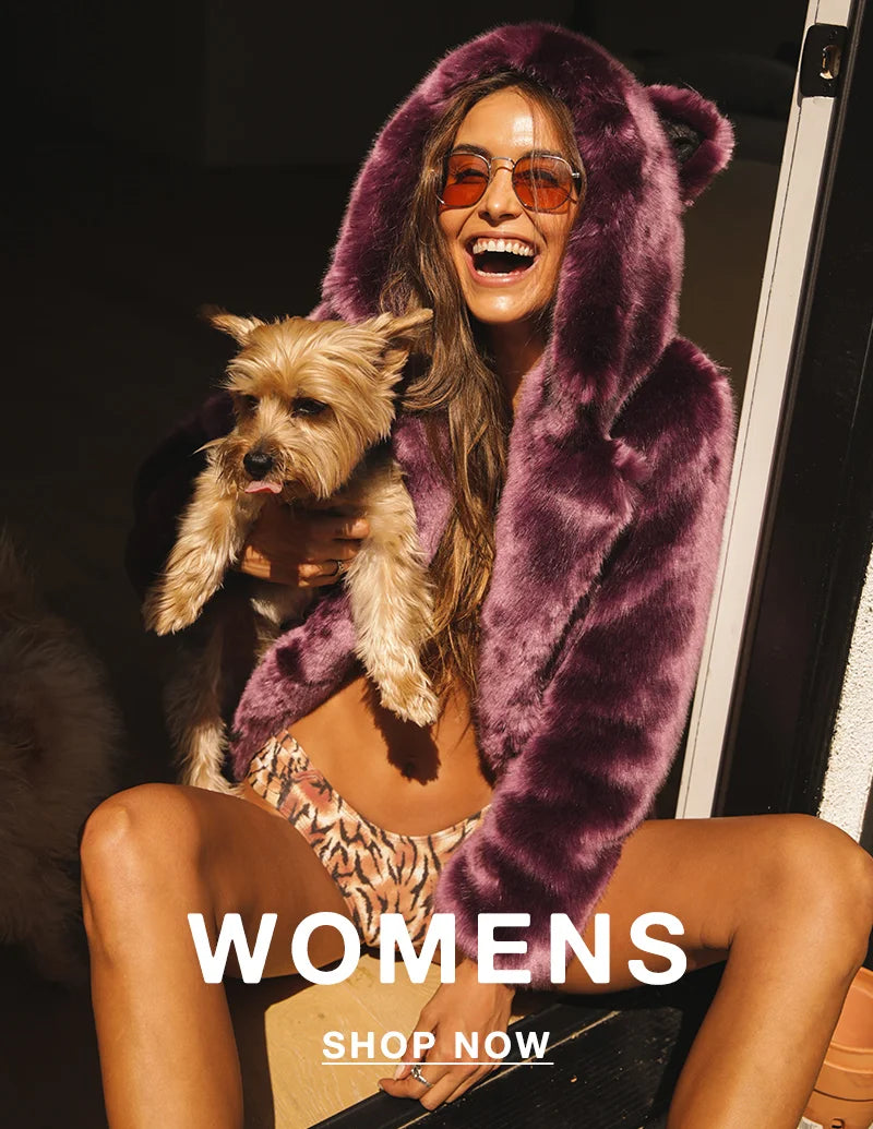 SMILING WOMAN HOLDING A SMALL DOG AND WEARING SUNGLASSES AND A LAVENDER FAUX FUR COAT WITH EARS