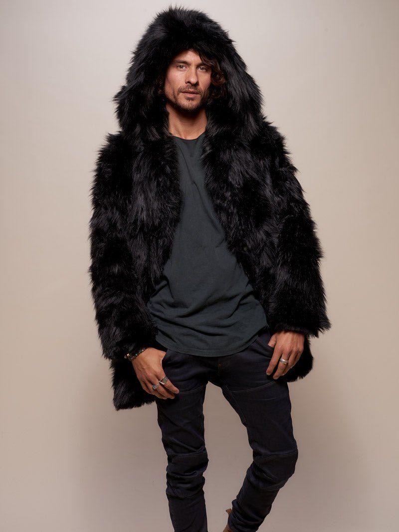 Handsome male model looking flirtatiously into the camera thumbs in his pants pockets, wearing the Black Wolf Faux Fur Coat with the hood on. 