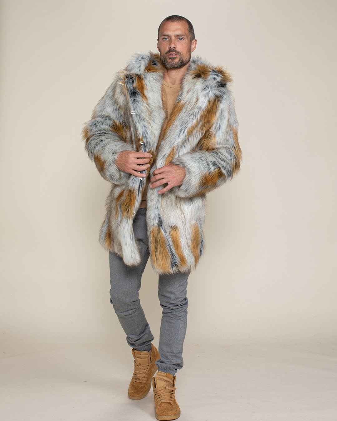 A handsome, buzz-cut male model with a beard and mustache, leaning slightly to one side while wearing his Arctic Fox faux fur jacket, holding the middle lapels closed.