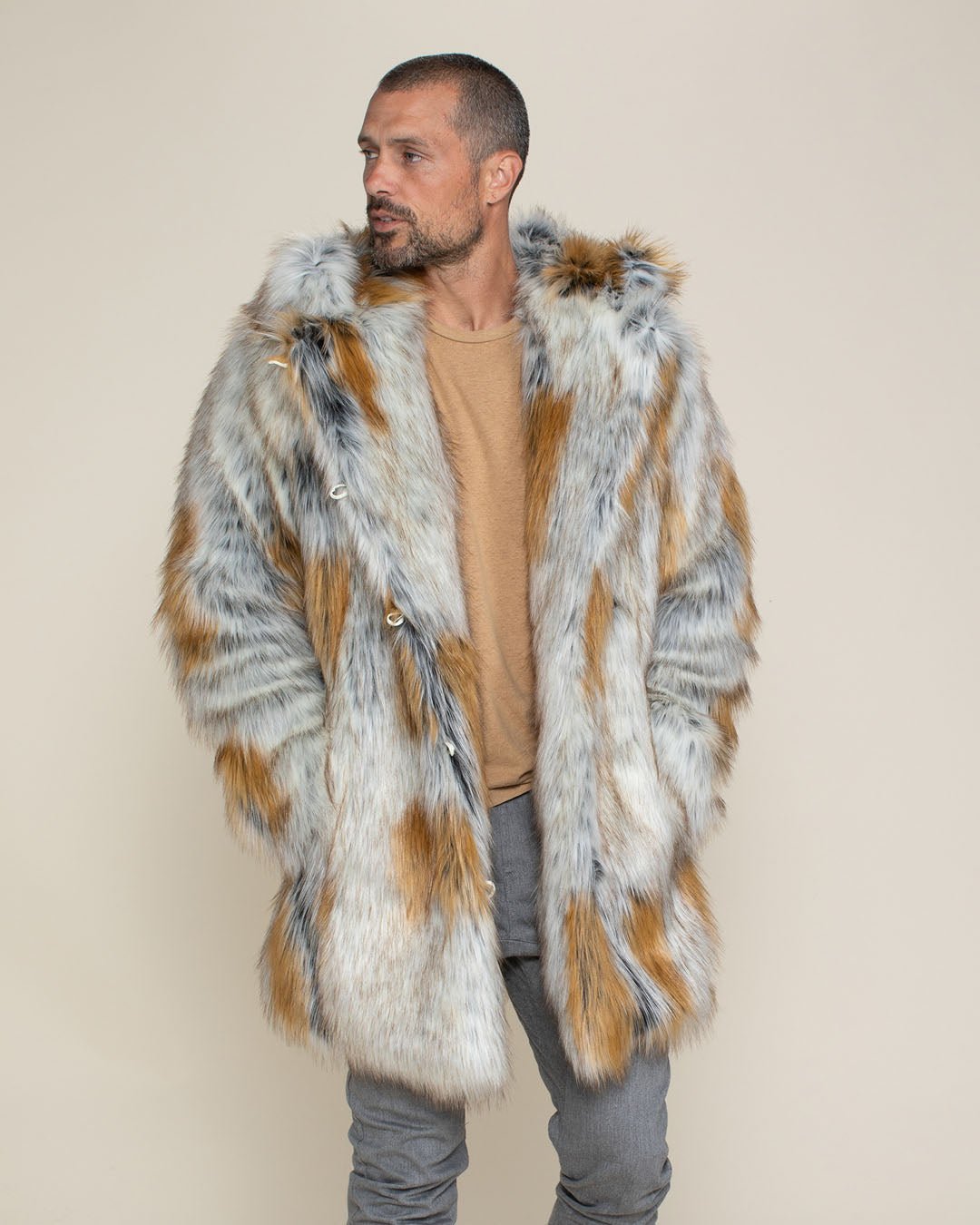 A handsome man with his hands in the pockets of his realistic Classic Arctic Fox fur coat, with the hood and ears down, looking to one side.