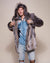 Young male model holding lapels of his fake fur grey wolf hooded coat open.