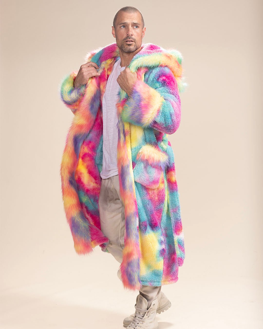 Man takes a step, holding lapels of open Rainbow Bear Faux Fur Robe, hood down, gazing inquisitively sideways. Bold, stylish comfort.