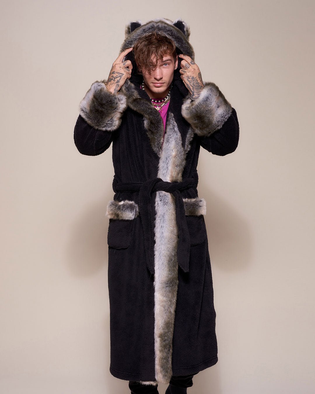 A male model holding either side of the faux fur Grey Wolf robe’s hood with ears, staring at the camera while wearing the robe closed with the belt.