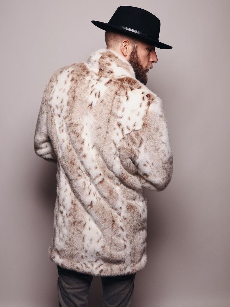 Back view of a male model with a beard and mustache wearing a fedora, head turned to one side wearing a fake fur Siberian Snow Leopard Coat.