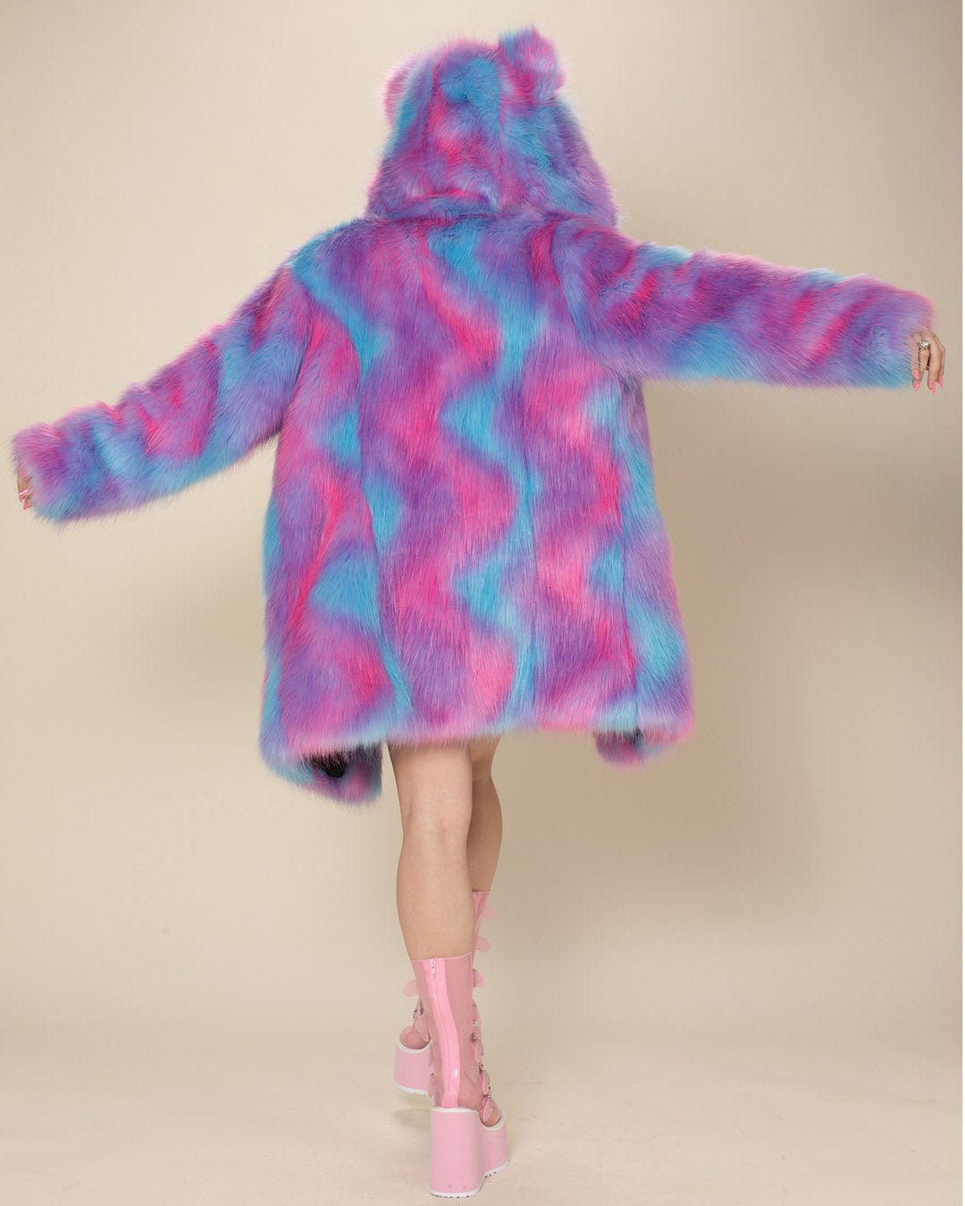 A female model with arms outstretched showcases the entire back of the Cotton Candy Bear vegan fur jacket, complete with the hood and ears up. 