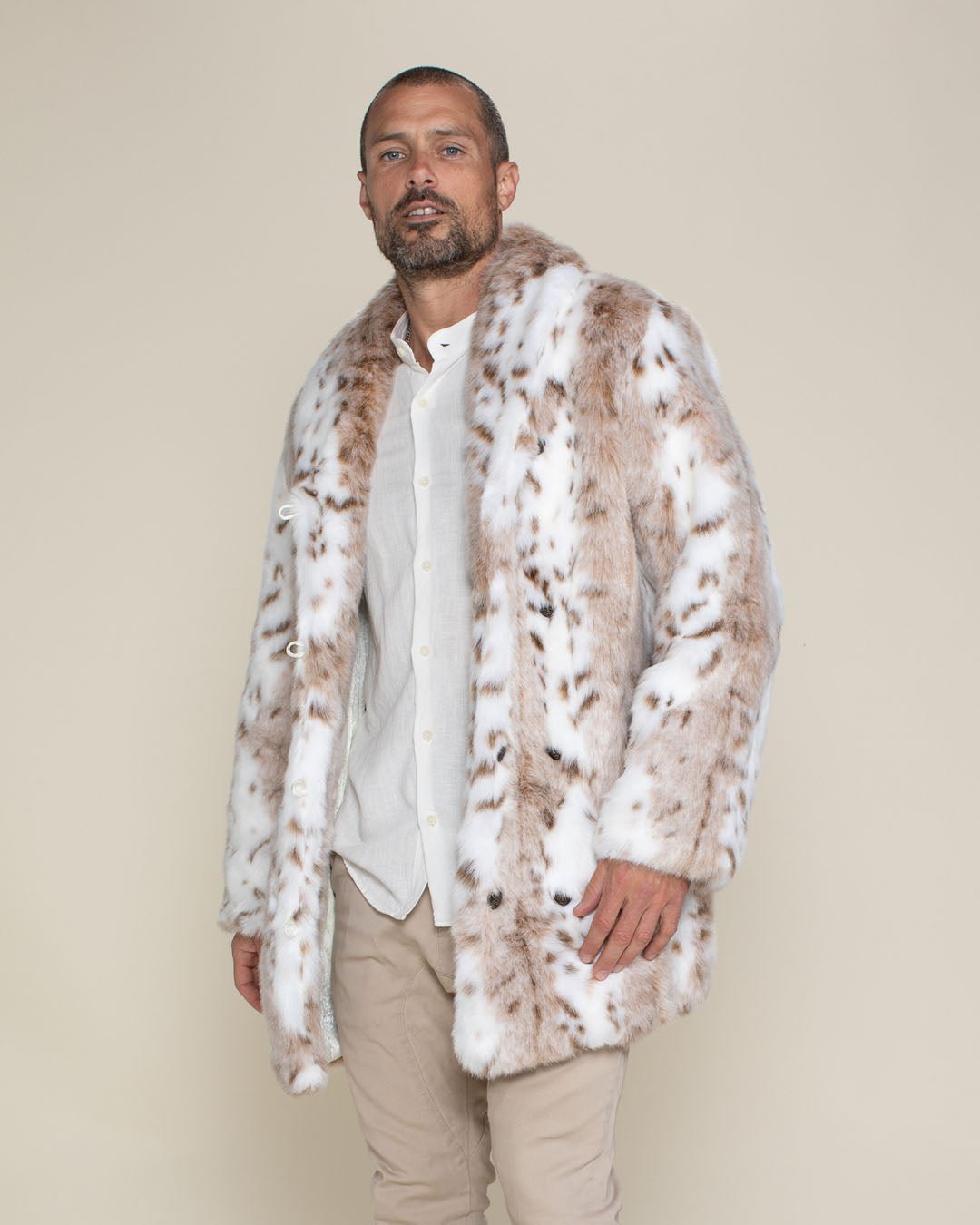 A handsome male model with a come-hither stare, standing with swagger in his collared Siberian snow leopard faux fur jacket.