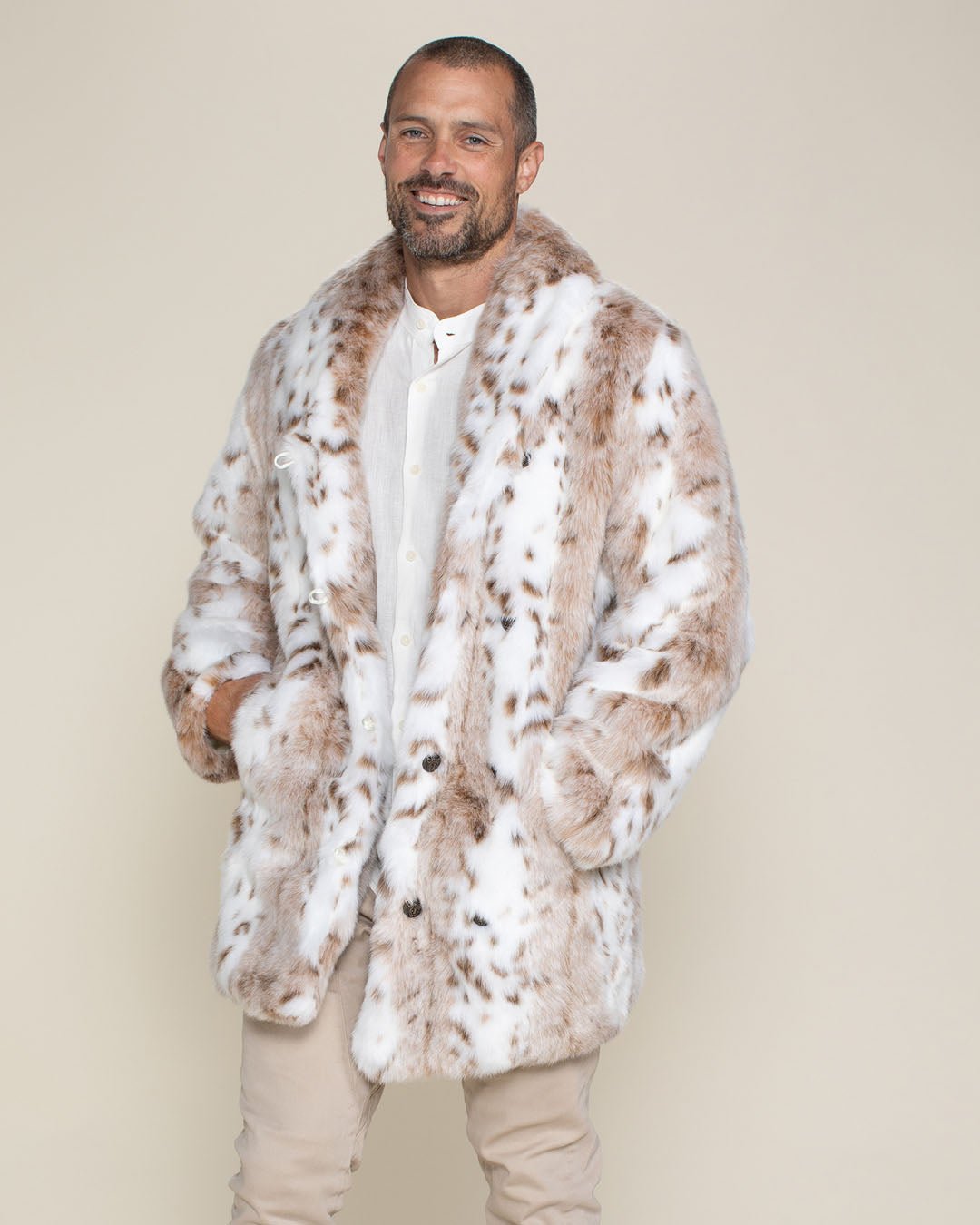 Back view of a male model with a beard and mustache wearing a fedora, head turned to one side wearing a fake fur Siberian Snow Leopard Coat.