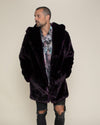 Male model looking to one side while wearing Dark purple Midnight Wolf fake fur jacket with hood down and hands in his pockets. 