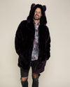 Smiling guy wearing hooded with ears, Midnight Wolf purple vegan fur coat with his hands in the pockets.