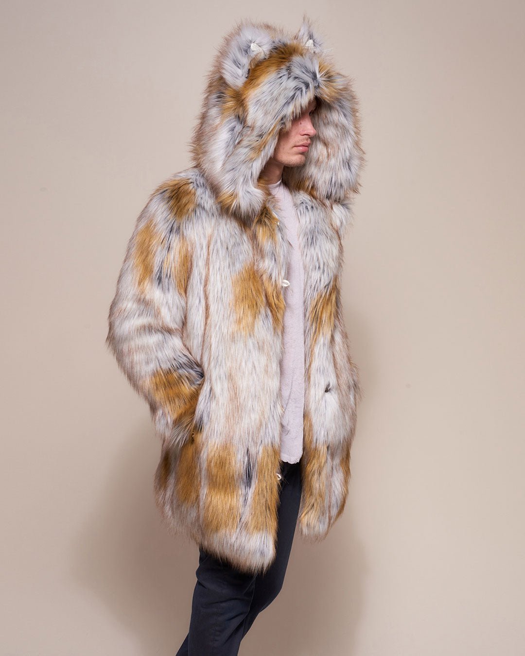 A guy wearing the faux fur coat called the Arctic Fox Classic, turned to one side with the hood and ears up, hands in his pocket.