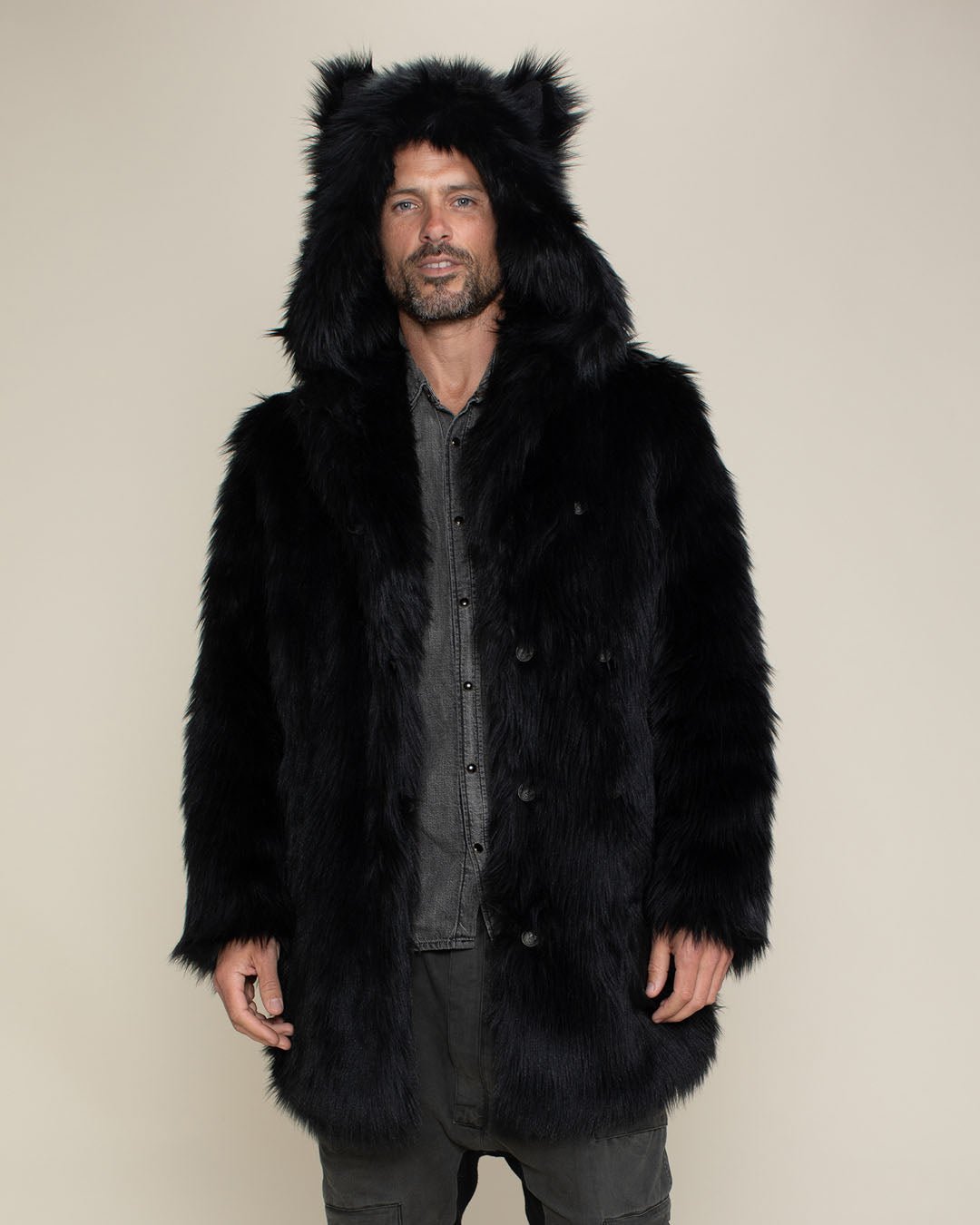 Man model with short beard and mustache wearing fake black wolf fur coat with hood and ears.