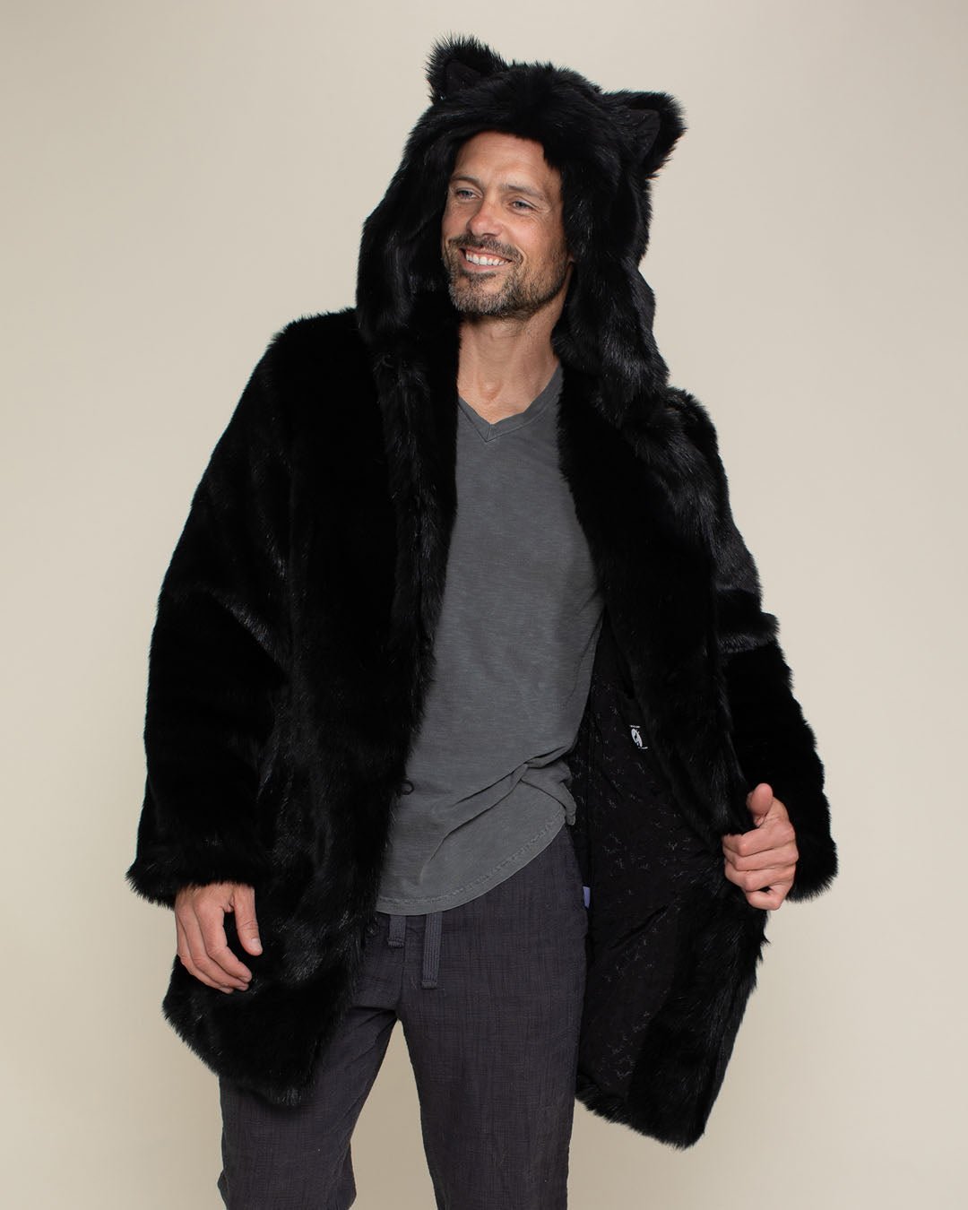 Dude smiling while wearing hooded and eared black panther fake fur coat while holding one side open showing inner pocket. 