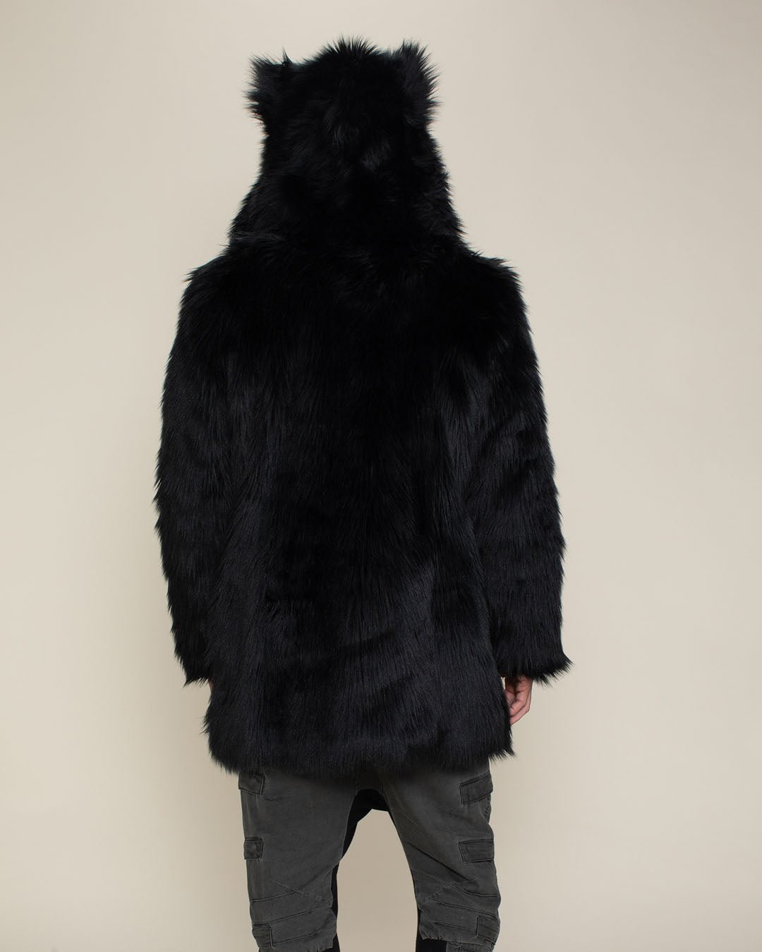 Male with entire back facing camera wearing artificial black wolf fur coat with hood and ears up. 