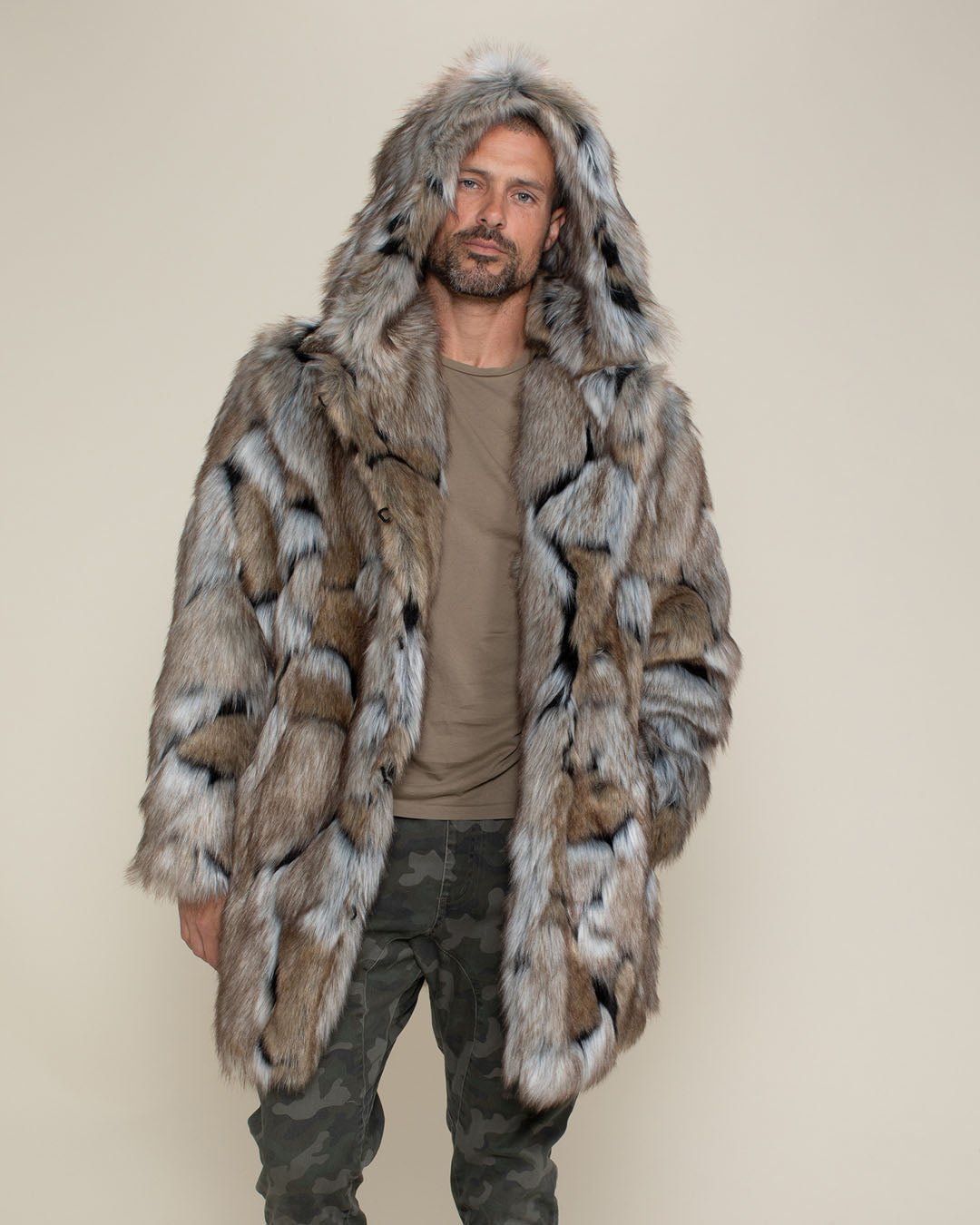 Handsome male model wearing the faux fur Hooded Wolverine coat, hood up, with one hand in his pocket.