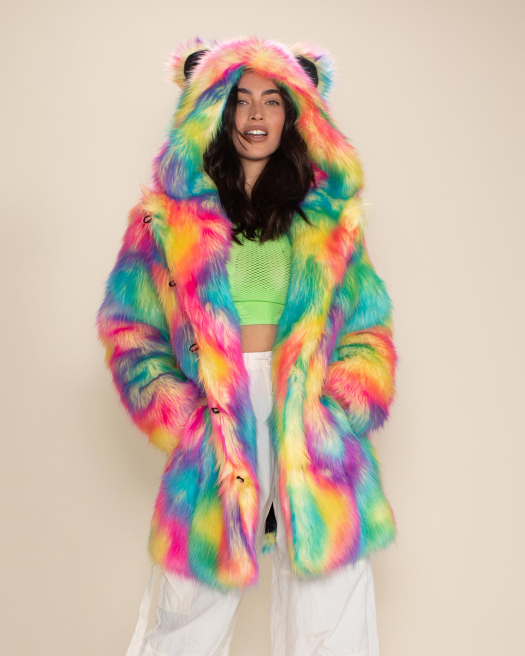 Sultry model with bright eyes and slightly open mouth, hands in pockets of Rainbow Bear Classic Faux Fur Coat with hood and ears up.