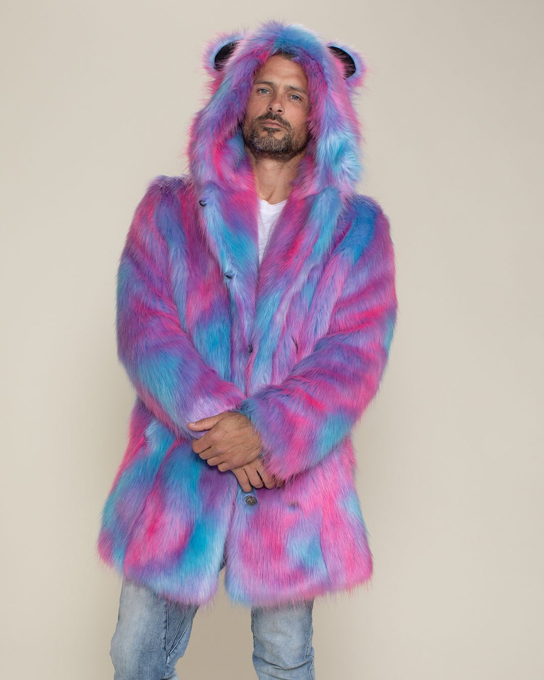 Serious handsome man with arms crossed at his waist, wearing the hood and ears up on the Cotton Candy Bear faux fur jacket.