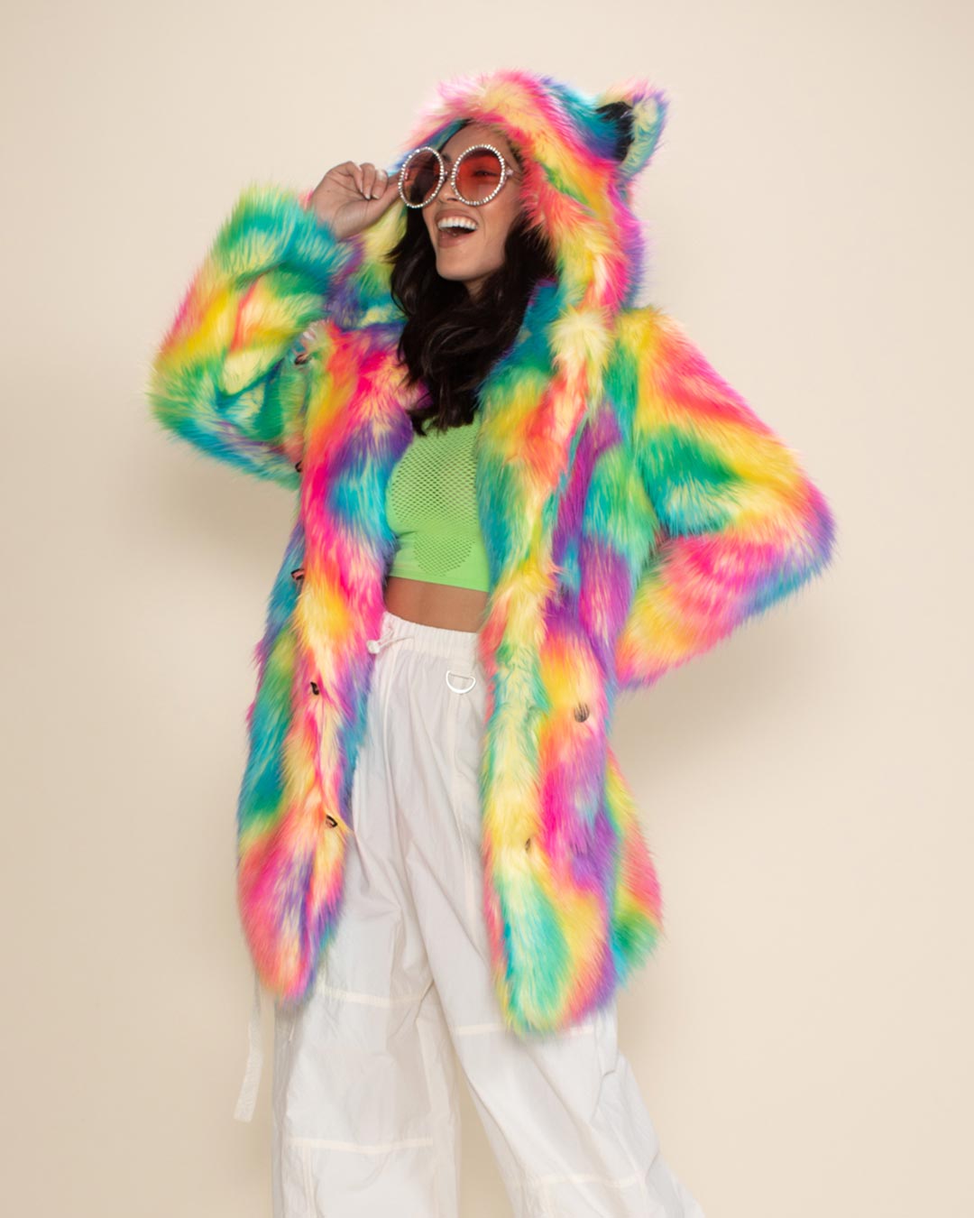 Pretty model in Rainbow Classic Faux Fur Coat, laughing with round orange sunglasses, facing to one side, hand on her hip.