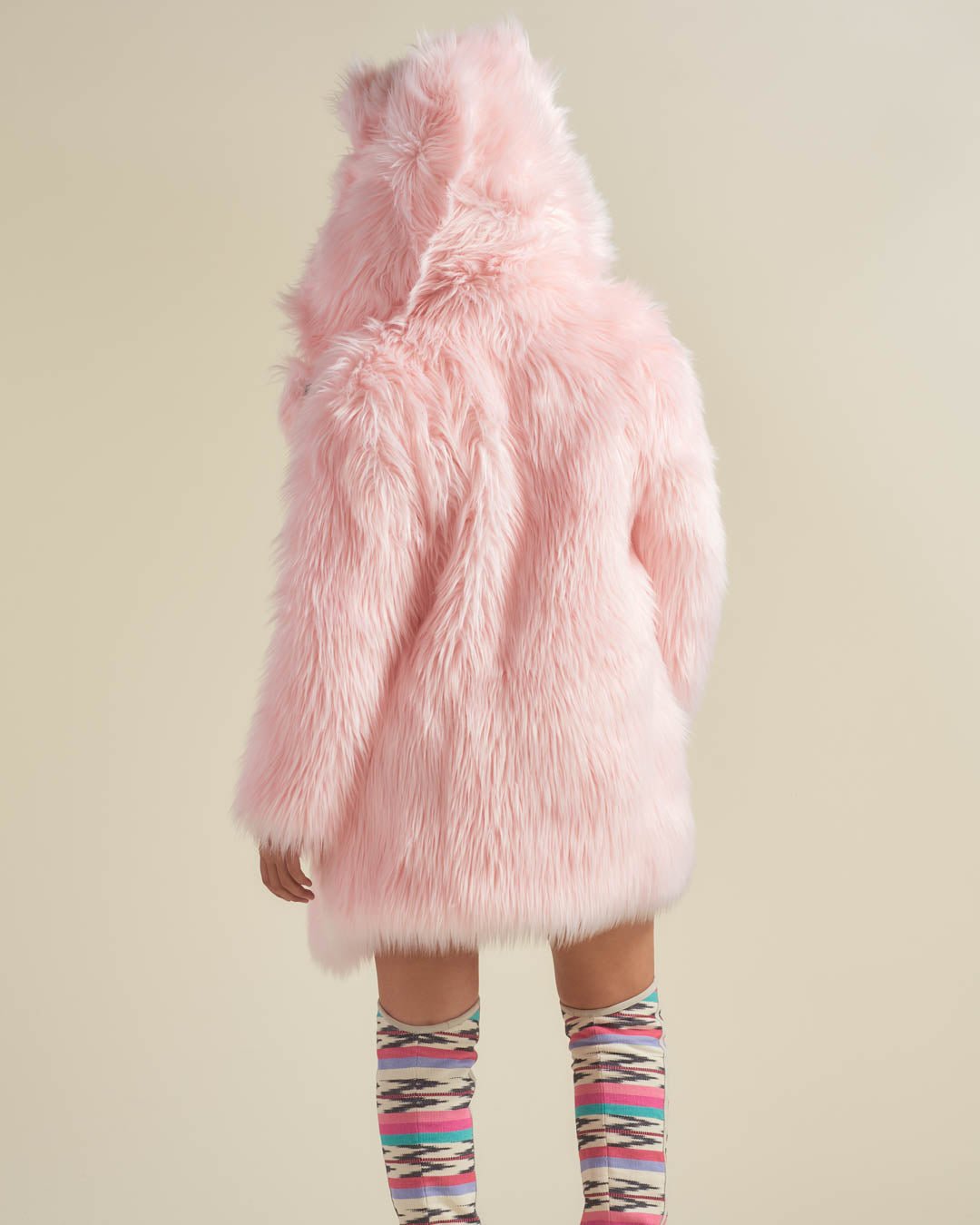 Girl in colorful knee-high socks wearing the faux fur Classic Flamingo Wolf coat, her back to the camera showcasing the coat.