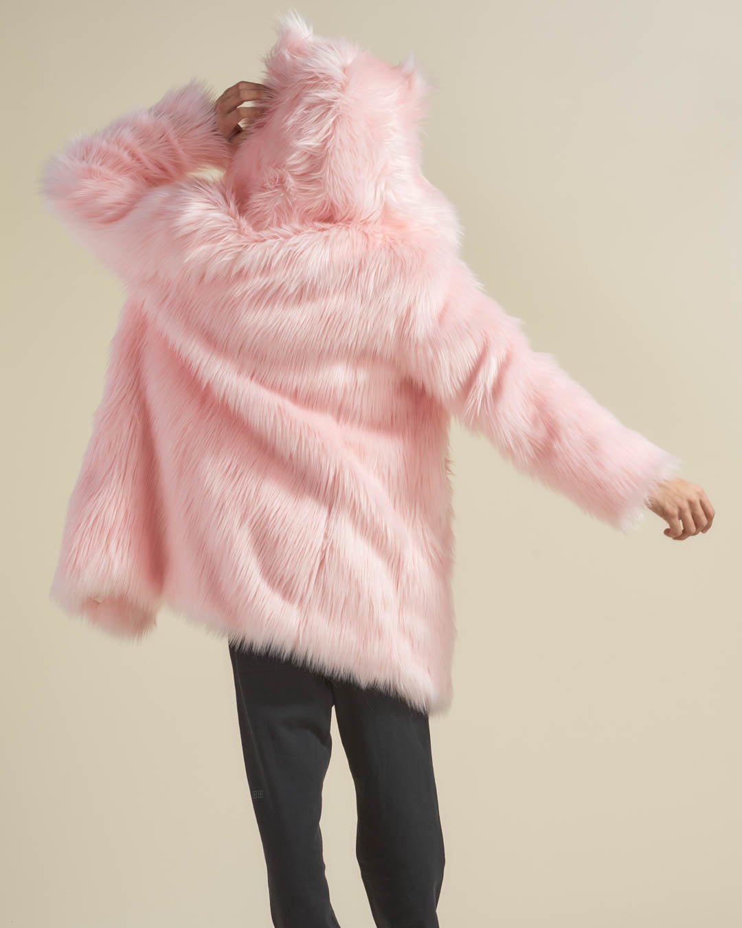 Guy wears Flamingo Wolf Classic Vegan Fur Coat, one arm out, the other on the hood, back turned to the camera.