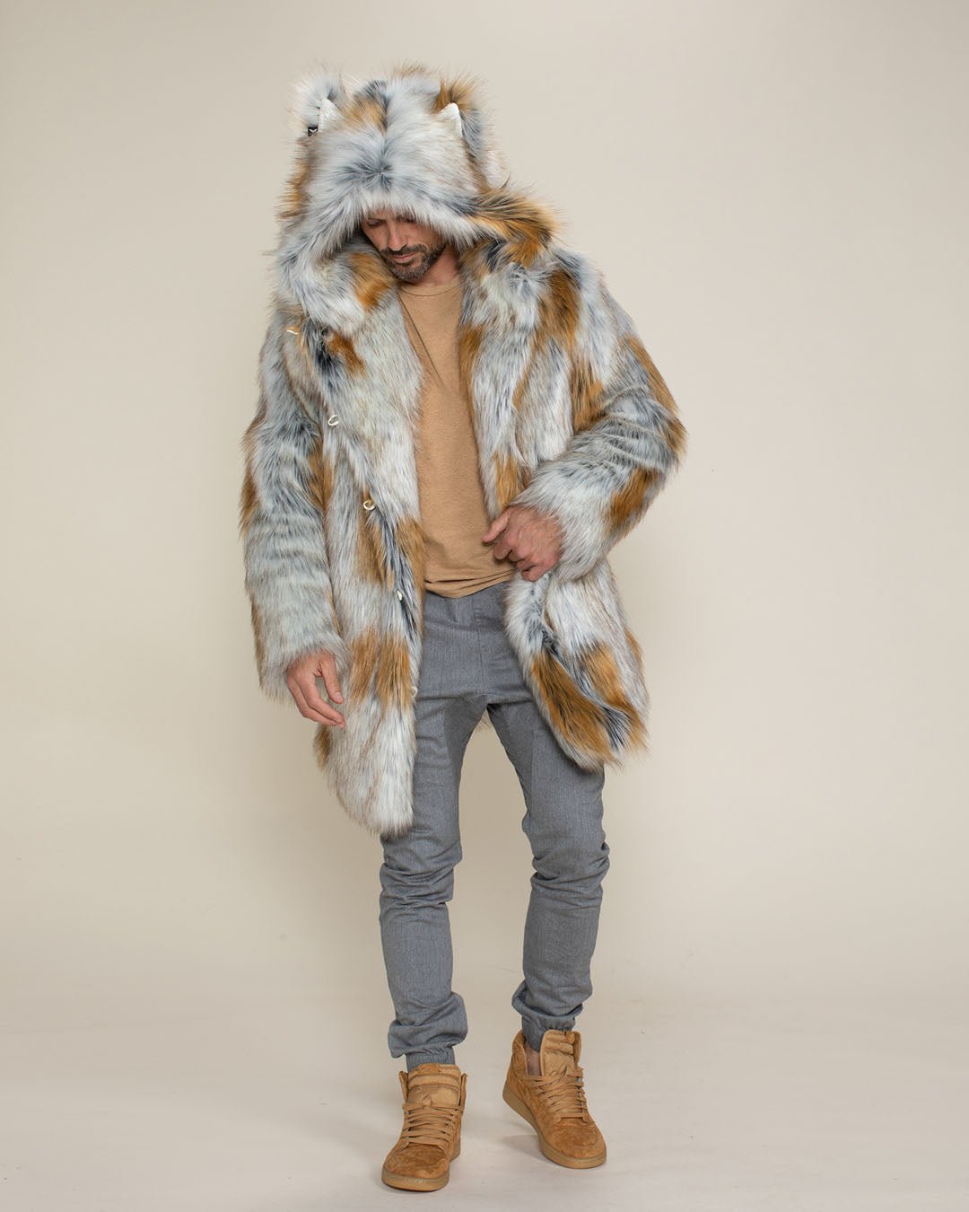 A dude looking directly at the camera with his hands in the pockets of his vegan Arctic Fox Classic coat, with the hood and ears up.