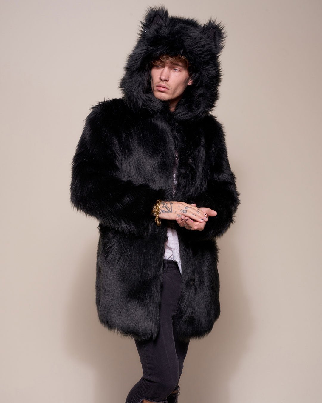 Guy looking to one side wearing realistic black wolf coat with buttoned at neck holding in place hood with ears. 