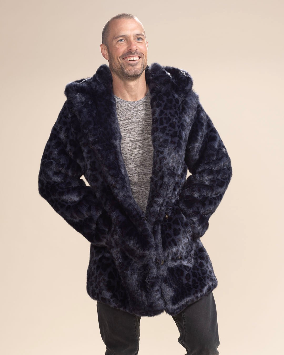 Smiling handsome man in the Collector Edition Indigo Leopard Faux Fur Coat, hands in pockets, with the bottom buttoned. Sleek and stylish look.