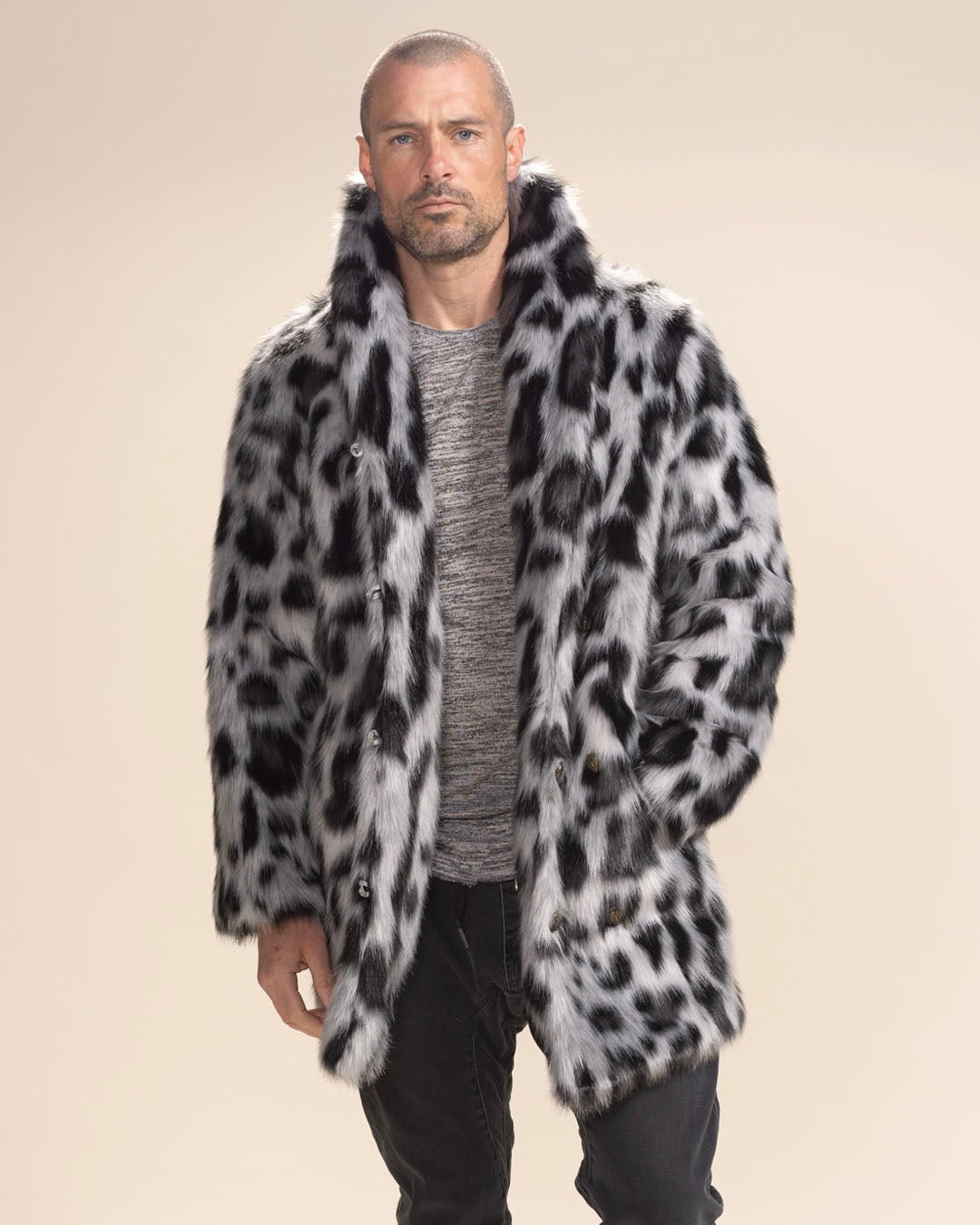 Dapper guy in Himalayan Collared Snow Leopard Vegan Fur Coat, one hand in pocket, staring intently at the camera. Chic faux fur style.