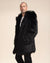 A handsome male model with a very short haircut is turned slightly to the side, looking away from the camera, wearing a faux fur jacket called the Black Wolf, with his hands in his pockets.