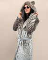 Chic woman in sunglasses wearing a silver leopard print faux fur coat with a belt, striking a stylish twist pose.