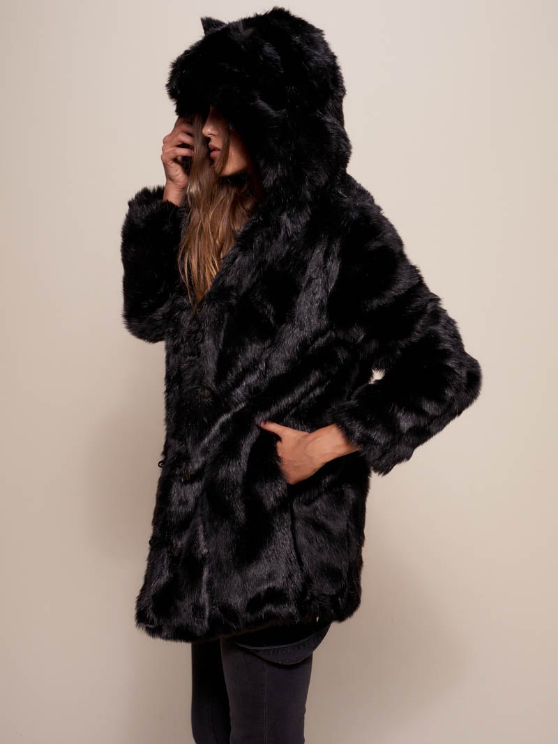 Female model facing the side with her hand in the pocket of a coat make of faux black panther fur.