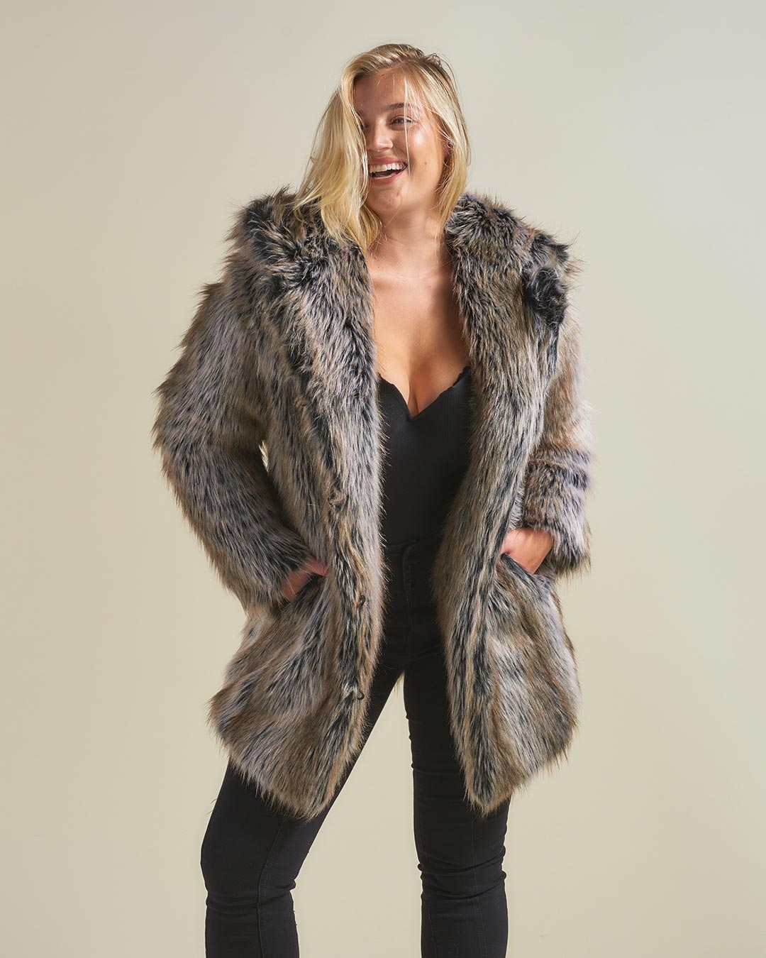 Blonde curvy woman wearing Grey Wolf Classic Faux Fur Coat by SpiritHoods. Her hands are in her pocket while she smiles.