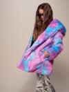 A female model with long brown hair partially covering her face, stands sideways in sunglasses, showing off the Cotton Candy Bear faux fur coat with her hands in the pockets.