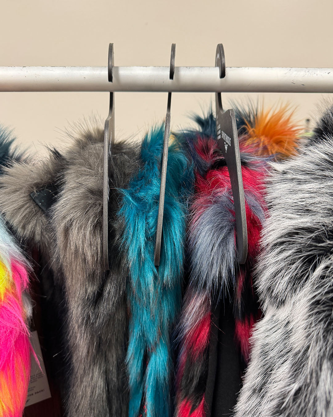 Cardboard hangers with faux fur clothing hanging on a rack