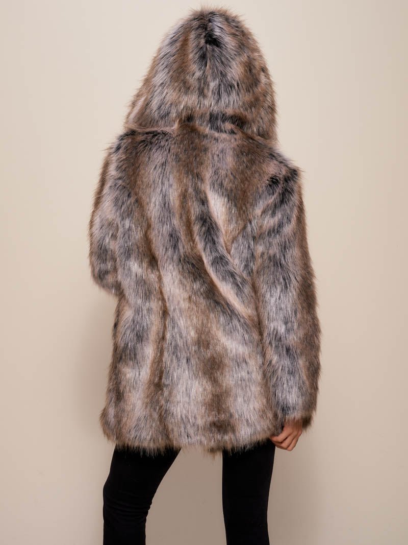 Female model with entire back to camera, wearing artificial hooded grey wolf coat, with the hood up on her head.