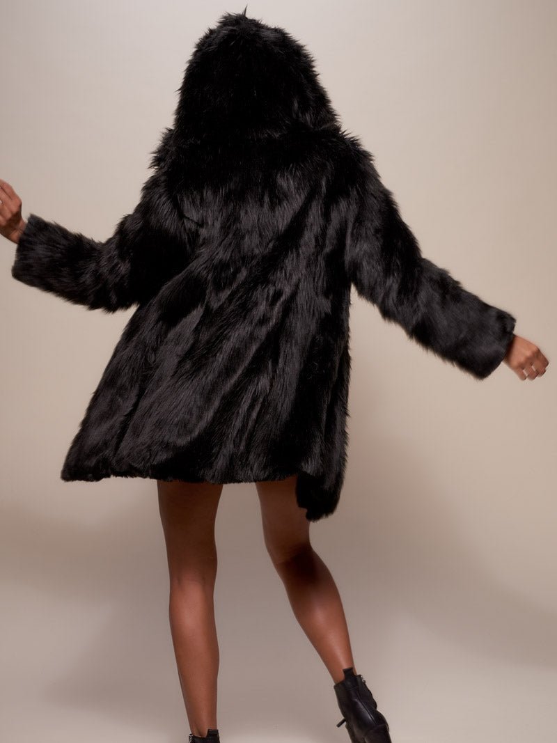 A girl performing a dance move with her arms out and her back to the camera, wearing the Hooded Black Wolf eco-fur coat with the hood up.